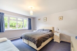 A bedroom with a bed, bedside tables, a window with curtains, and framed pictures on the wall. - 4 Bed in Ilkley (oc-ds168) (Ilkley)