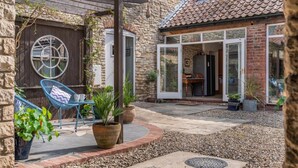 A stone house with a patio area featuring a wooden pergola, a blue chair, and potted plants. - 4 Bed in Cawton (oc-t32408) (Cawton)