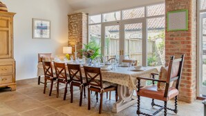 A dining area with a table set for six, surrounded by wooden chairs, a chandelier, and a stone wall. - 4 Bed in Cawton (oc-t32408) (Cawton)