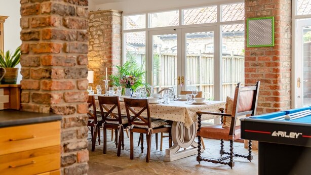 A dining area with a brick wall, a pool table, and a window with a view of a wooden fence. - 4 Bed in Cawton (oc-t32408) (Cawton)