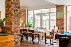 A dining area with a brick wall, a pool table, and a window with a view of a wooden fence. - 4 Bed in Cawton (oc-t32408) (Cawton)