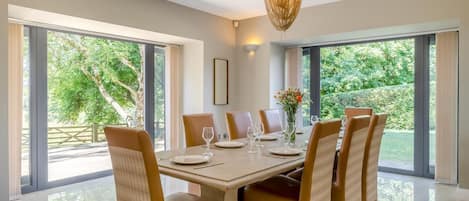 A dining area with a large table, chairs, and a chandelier.