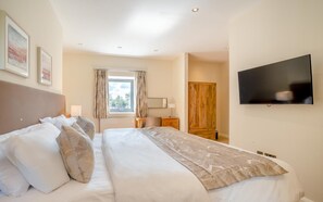 A hotel room with a bed, a television, a window with curtains, and a wooden wardrobe.