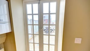 Een kamer met een grote glazen deur naar buiten, een witte radiator en een lichtschakelaar aan de muur.