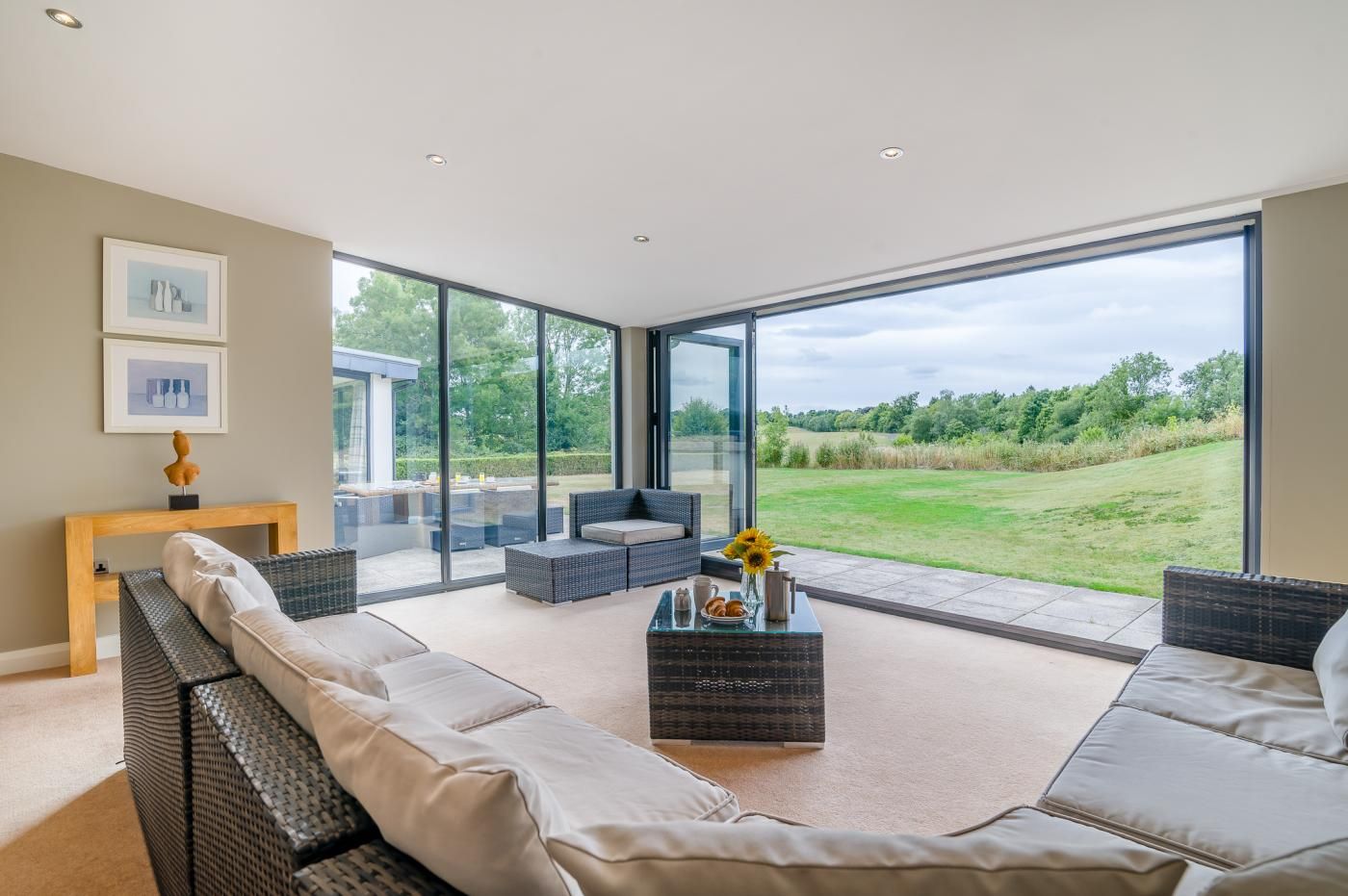 A modern living room with a large glass door leading to a garden.