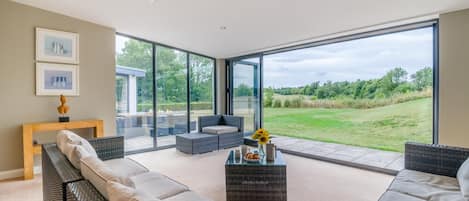 A modern living room with a large glass door leading to a garden.
