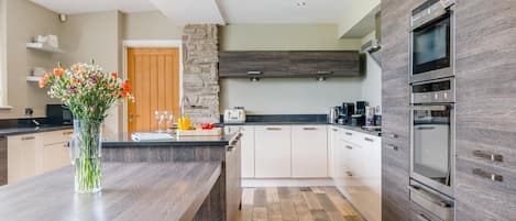 A modern kitchen with a central island, a stone accent wall, and built-in appliances.