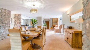 A dining area with a wooden table and chairs, a stone wall, and a modern pendant light. - 4 Bed in Catsash (oc-u32332) (Newport)