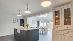 Una cocina moderna con una isla central, muebles oscuros e iluminación colgante.