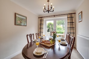 A dining room with a round table set for breakfast, featuring croissants, fruit, and orange juice. - 3 Bed in Ravenscar (oc-sa397) (Ravenscar)