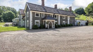 A large, two-story stone building with a gravel driveway and a small lawn area. - 7 Bed in Northrepps (oc-n32549) (Overstrand)