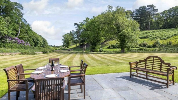 An outdoor dining area with a table set for four, surrounded by chairs, and a bench. - 7 Bed in Northrepps (oc-n32549) (Overstrand)