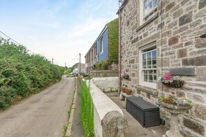 A narrow street with stone buildings, one with a blue exterior and ivy, and flower boxes on the walls. - 2 Bed in Higher Penponds (oc-h32383) (Camborne)