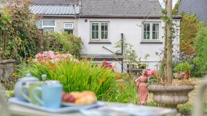 Een tuin met een tafel, een beeld en een huis op de achtergrond.