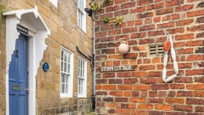 A stone building with a blue door labeled 'Storm Cottage.' - 2 Bed in Whitby (oc-r579) (Robin Hood's Bay)