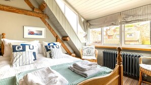 Ein Schlafzimmer mit Bett, Kissen, einem Sessel, einem Fenster mit Ausblick und einer Heizung.