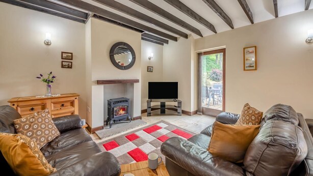 A living room with a fireplace, leather sofas, a TV, and a large window. - 2 Bed in Whitby (oc-y003) (England)