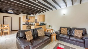 A modern living room with a leather sofa, wooden dining table, and a kitchen in the background. - 2 Bed in Whitby (oc-y003) (England)