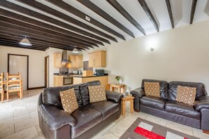 Ein modernes Wohnzimmer mit einer Ledersofa, einem Holzesstisch und einer Küche im Hintergrund.