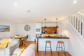 Eine moderne Küche mit einer zentralen Kochinsel, Holzschränken und Pendelleuchten.
