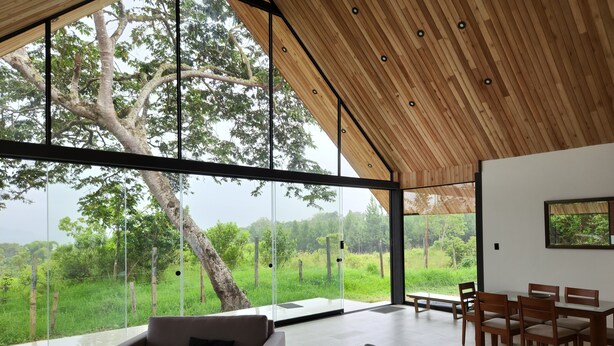 A spacious living area with a large glass wall offering a view of a lush landscape.