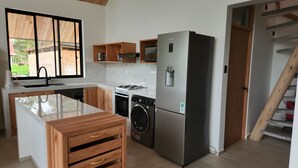 A modern kitchen with a stainless steel refrigerator, built-in oven, and washing machine.