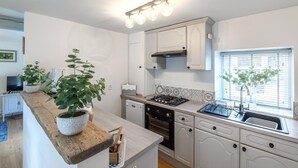 A modern kitchen with white cabinetry, a built-in stove, and a window with blinds. - 2 Bed in Pateley Bridge (oc-ds127) (Castlestead)