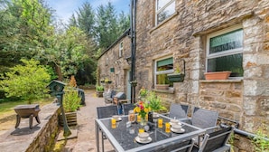 A stone building with a patio area featuring outdoor seating and a grill. - 5 Bed in Snaizeholme (oc-w32200) (Hawes)