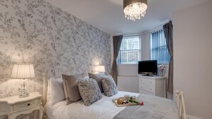 A bedroom with a bed, two bedside tables, a TV, and a window with curtains. - 2 Bed in Whitby (oc-w945) (Whitby)