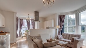 A modern living room with a sofa set, a dining area, and a view of a historic building. - 2 Bed in Whitby (oc-w945) (Whitby)