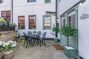 A courtyard with a table and chairs, a potted tree, and a building with a sign reading '6 Hyndings Yard'. - 2 Bed in Whitby (oc-h32509) (Whitby)