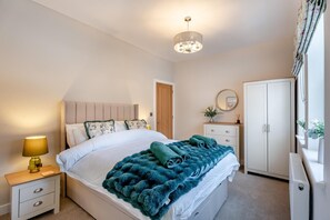A bedroom with a bed, bedside table, lamp, dresser, wardrobe, and a chandelier. - 2 Bed in Whitby (oc-h32509) (Whitby)