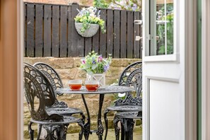 A patio with a table and chairs, a potted plant, and a hanging basket of flowers. - 2 Bed in Whitby (oc-h32509) (Whitby)
