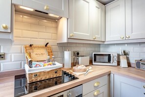 Eine moderne Küche mit weißen Schränken, einer Mikrowelle, einem Toaster und einem Korbwannen mit einer Flasche.