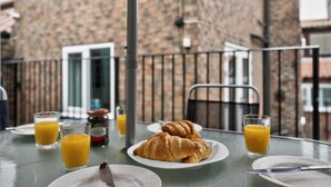 A breakfast setup with croissants, orange juice, and a knife on a table outside a building with a brick facade. - 2 Bed in Whitby (oc-w793) (Whitby)