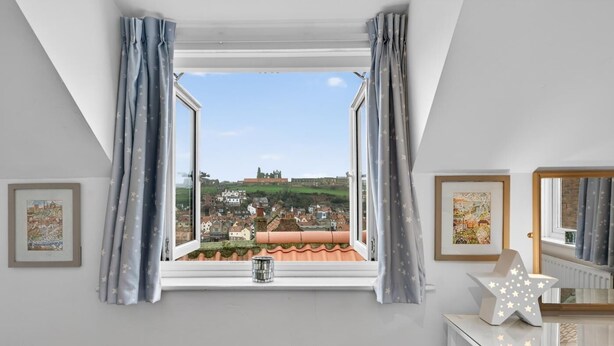 A room with a view of a town, a window with curtains, a star-shaped light, and framed pictures on the wall. - 2 Bed in Whitby (oc-w793) (Whitby)