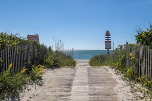 A wooden boardwalk leading to a beach with a lighthouse in the distance. - The Griffin House Main Level, Almost Oceanfront Duplex with Beach Access across (Pine Knoll Shores)
