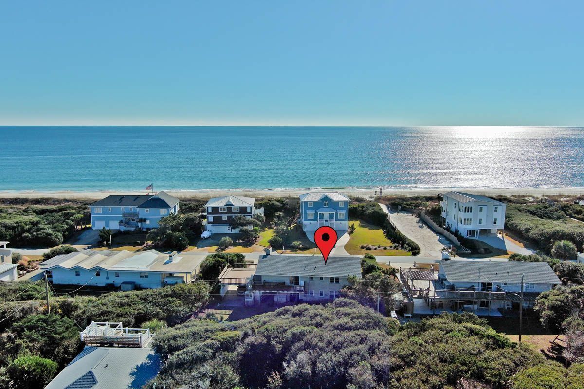A coastal residential area with houses, a beach, and a clear sky.