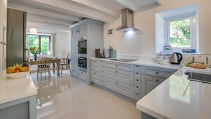 A modern kitchen with a central island, built-in appliances, and a dining area with a view. - 3 Bed in Gunwalloe (oc-p00858) (Gunwalloe)