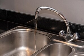 Ein Spülbecken aus Edelstahl mit einem modernen Wasserhahn.