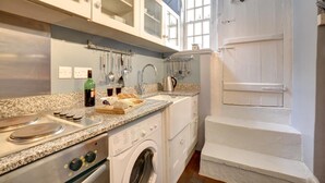 A kitchen with granite countertops, a built-in oven, a washing machine, and a window with a view of the outside. - 3 Bed in Whitby (oc-r020) (Robin Hood's Bay)