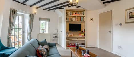 A living room with a sofa, a coffee table, a bookshelf, and a television.