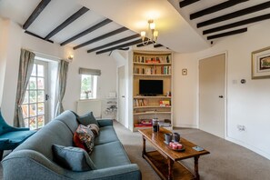 A living room with a sofa, a coffee table, a bookshelf, and a television. - 3 Bed in Kirkbymoorside (oc-y100) (Kirkbymoorside)