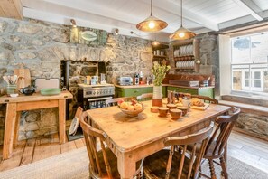Une cuisine rustique avec des murs en pierre, des meubles en bois et une cheminée en pierre.