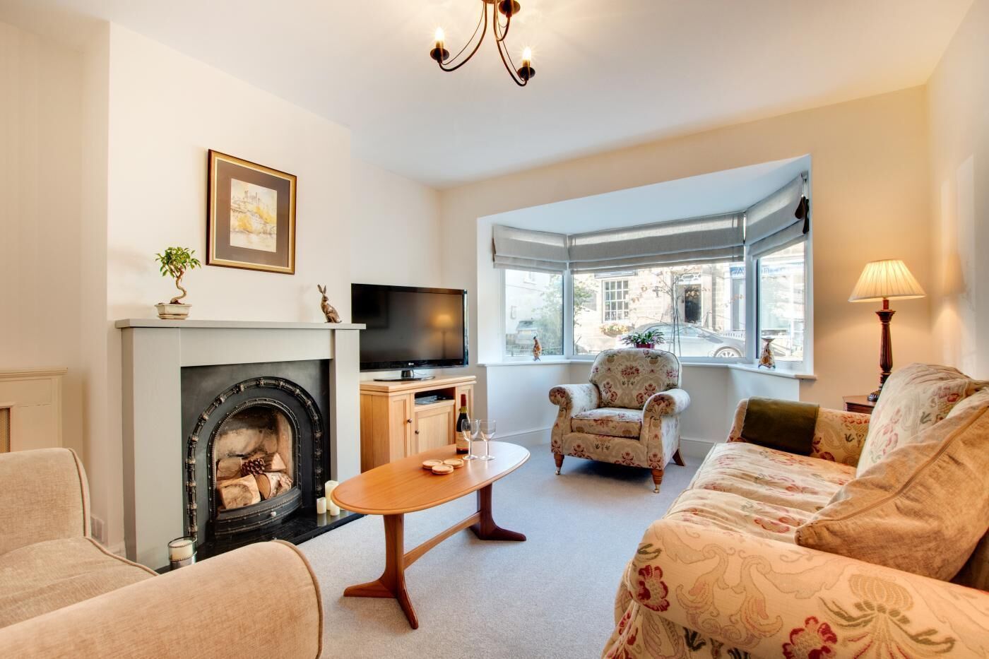 A cozy living room with a fireplace, a television, a comfortable sofa, and a window with a view of the city.