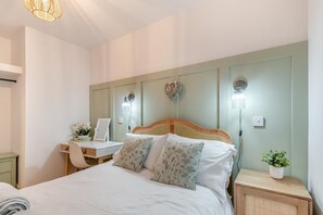 A bedroom with a bed, bedside tables, a desk, and a chair. - 2 Bed in Saundersfoot (oc-p32329) (Saundersfoot)