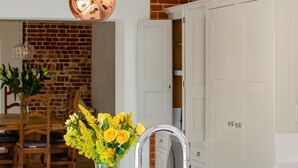 A modern kitchen with white cabinetry, a stainless steel sink, and a vase of yellow flowers. - 3 Bed in Banningham (oc-rftg) (Banningham)