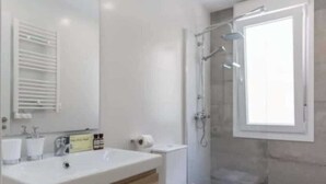 A modern bathroom with a large sink, mirror, and shower. - AR Plaza Castilla spacious and modern apartment (Madrid)