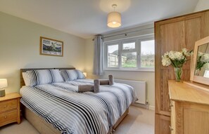 A bedroom with a bed, bedside table, lamp, window, and a mirror.