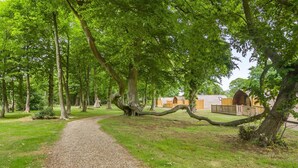 A gravel path leading through a park with trees and wooden structures in the background.